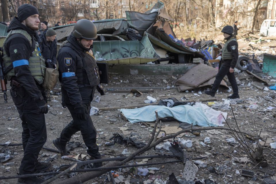 Ukrainian service members stand next to a dead body at a residential district that was damaged by shelling in Kyiv, Ukraine, March 18, 2022, as Russia's invasion of Ukraine continues. (CNS photo/Marko Djurica, Reuters)