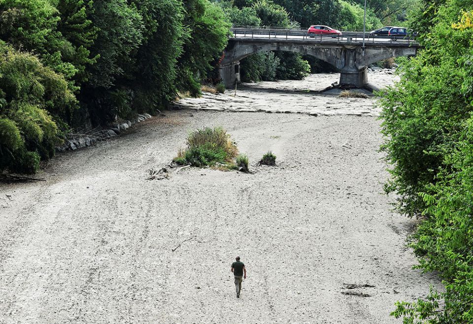 A man walks on the dry riverbed of the Sangone River, a tributary of the Po River, June 19 in Beinasco, Turin, Italy. Italy is experiencing its worst drought in 70 years. (CNS/Reuters/Massimo Pinca)