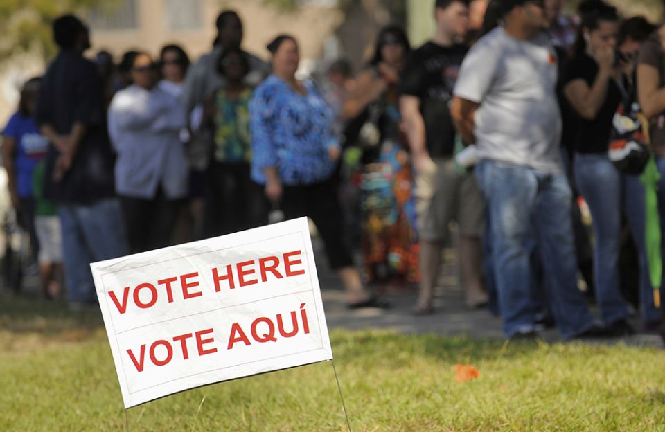 A sign in English and Spanish is seen as people wait to vote in 2012 outside a polling place in Kissimmee, Florida. (CNS/Reuters/Scott A. Miller)